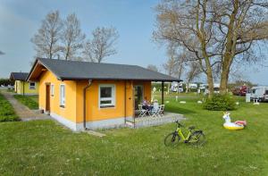 阿尔滕基兴Knaus Camping- und Ferienhauspark Rügen的一座黄色的小房子,人们坐在院子里