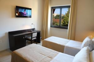 安科纳Albergo Cantiani的酒店客房设有两张床、一张桌子和一台电视。
