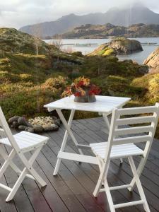 莱克内斯Unique private cabin in Lofoten的甲板上的白色野餐桌和两把椅子