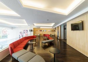 波尔图Moov Hotel Porto Centro的一间设有红色沙发和电视的等候室