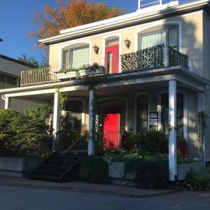 拜圣保罗La CAMPAGNE au centre-ville de Baie-Saint-Paul UNIQUE的白色的房子,有红色的门和楼梯