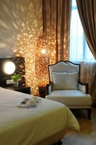 麻坡丹戎别墅旅馆的一间卧室配有一张床、一把椅子和一盏灯