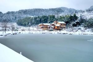 张家界张家界水湧金江民宿的一座有雪覆盖的湖,后面有一座房子
