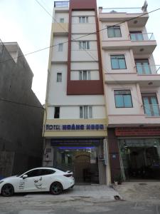 Dĩ AnHoang Ngoc Hotel的停在大楼前的白色汽车