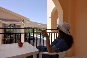 阿里拉斯Makris Apartments Arillas Corfu的坐在桌子旁的女人,喝一杯酒