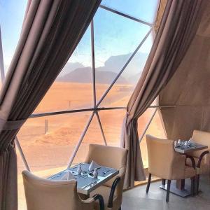 瓦迪拉姆Wadi Rum Bubble Luxotel的配有大窗户的客房内的桌椅