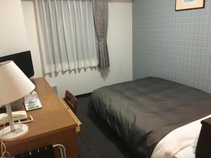 松本Garden Hotel Matsumoto的一间卧室配有一张床和一张带台灯的书桌