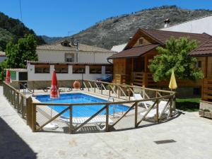 阿罗约弗里奥Cabañas de Madera El Rinconcillo的一个带木栅栏和房屋的游泳池