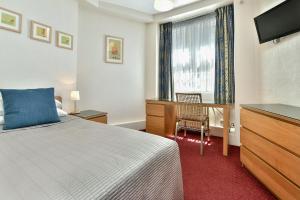 伦敦欧罗酒店的一间卧室配有一张床、一张书桌和一台电视
