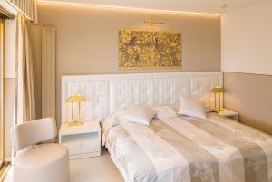 阿斯科纳阿斯科纳酒店的卧室配有一张白色大床和一把椅子