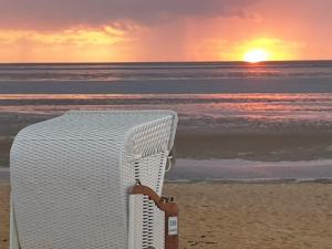 库克斯港Haus Frauenpreiss 67的日落时坐在海滩上的藤椅