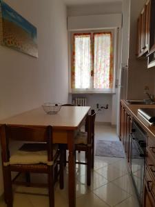 帕尔马Appartamento Soleluna的厨房配有木桌、椅子和窗户。