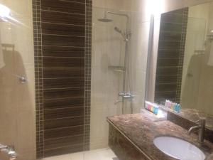 利雅德Arjaan Altakhassusi Hotel Suites的浴室配有盥洗盆和带镜子的淋浴