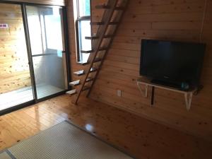 南阿苏村熊本南麻生小亚州旅馆的一间带电视和木墙的客厅