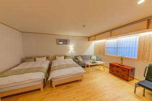 东京YADOYA Uguisu的一间卧室配有两张床、一张沙发和一张桌子
