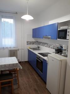 陶波尔曹Sport Apartman Tapolca的厨房配有蓝色橱柜和白色炉灶烤箱。