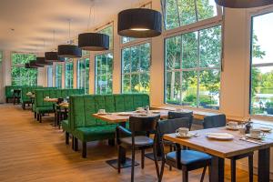 布隆Lake House Plön的餐厅设有桌子和绿色椅子以及窗户。