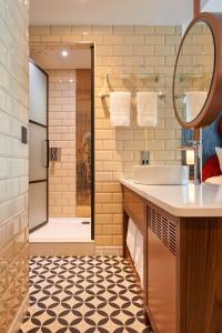 都柏林Hard Rock Hotel Dublin的浴室配有盥洗盆和带镜子的淋浴