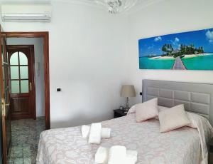 大加那利岛拉斯帕尔马斯Balcón de la Bahía Gran Canaria的卧室配有一张床,墙上挂有绘画作品