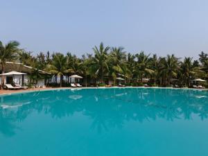 朗姑村兰珂海滩度假酒店的一座种植了棕榈树的大型蓝色游泳池