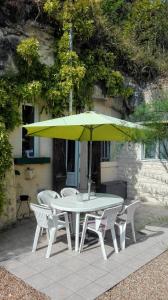 吕讷Troglo Papillon的白色的桌子和椅子,配有黄色的雨伞