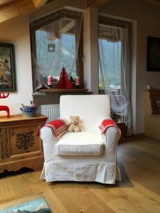 拉松迪索帕拉Mansarda Dolomiti的客厅里白椅子上的泰迪熊