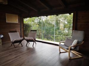 Monzuno迪玛莎农家乐公寓的客厅配有两把椅子和大窗户