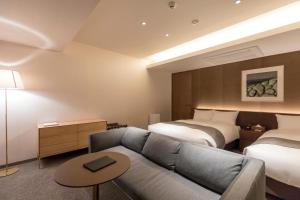 京都yoin hotel kyoto gion的酒店客房,设有两张床和一张沙发