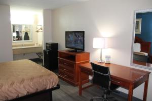 塔斯卡卢萨Americas Best Value Inn Tuscaloosa的酒店客房配有书桌、床和电视。