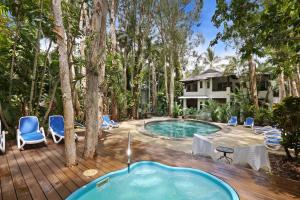 棕榈湾礁石宁静棕榈湾酒店的一个带椅子的甲板上的热水浴缸和一座房子
