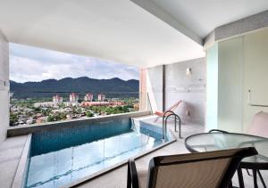 峇六拜槟城丽昇豪华套房的阳台设有游泳池和桌椅。