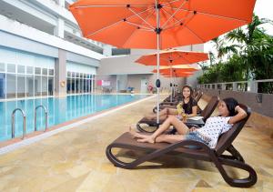 峇六拜槟城丽昇豪华套房的三名妇女坐在游泳池旁的躺椅上