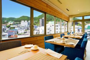 函馆康考迪亚别墅Spa度假酒店的餐厅设有木桌和蓝色的椅子及窗户。