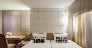 曼谷Tango Vibrant Living Hotel - SHA Extra Plus的一间卧室配有两张床、一张桌子和一张书桌