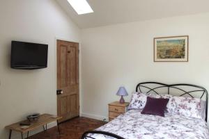 Praze an BeebleThe Piggery at Moorfield Barns的卧室配有一张床,墙上配有电视。