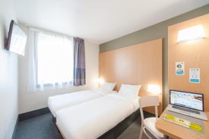 Saint-Didier-sous-AubenasB&B HOTEL Aubenas的酒店客房设有两张床和一张书桌上的笔记本电脑