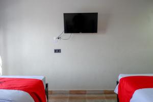 PalopoRedDoorz Syariah At Jalan Jenderal Sudirman Palopo的一间卧室设有两张床,墙上设有一台平面电视。