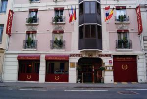 鲁昂康苏尔鲁昂酒店的一条城市街道上与酒店同一栋粉红色的建筑