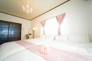四日市Yokkaichi Large House in Shimizucho nearby Yokkaichi STN的卧室配有白色床,上面有粉红色的花朵