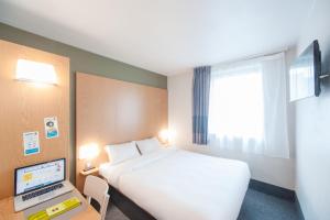 里永B&B HOTEL Clermont-Ferrand Nord Riom的酒店客房配有一张床、一张书桌和一台笔记本电脑