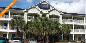 查尔斯顿InTown Suites Extended Stay North Charleston SC - Airport的一座楼前的棕榈树旅馆