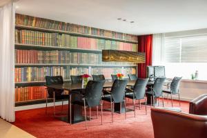阿姆斯特丹阿姆斯特丹斯特劳戴克智选假日酒店的一间用餐室,配有桌椅,位于书籍前