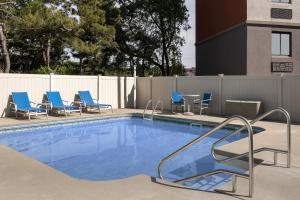 索格斯Holiday Inn Express Boston - Saugus, an IHG hotel的一个带蓝色椅子和围栏的游泳池