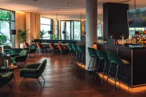 柏林柏林市中心东普伦茨劳贝格假日酒店的一间设有绿色椅子的餐厅和一间酒吧