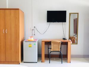 南府潘提普酒店的客房设有桌子、冰箱和电视。