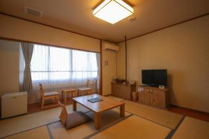 由布市湯布院 旅館 やまなみ Ryokan YAMANAMI的客厅配有桌子和电视