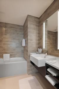 迪拜Millennium Executive Apartments Mont Rose的浴室设有2个水槽、浴缸和镜子