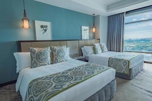 马尼拉Ascott Makati的酒店客房设有两张床和窗户。