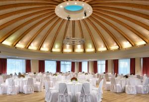 佩罗UNAHOTELS Expo Fiera Milano的一个带白色桌椅的宴会厅和大型天花板