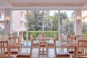雅典Civitel Attik Rooms & Suites的一间带桌椅的用餐室和大窗户